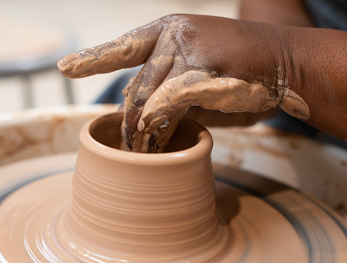 Hands throwing a pot on a wheel